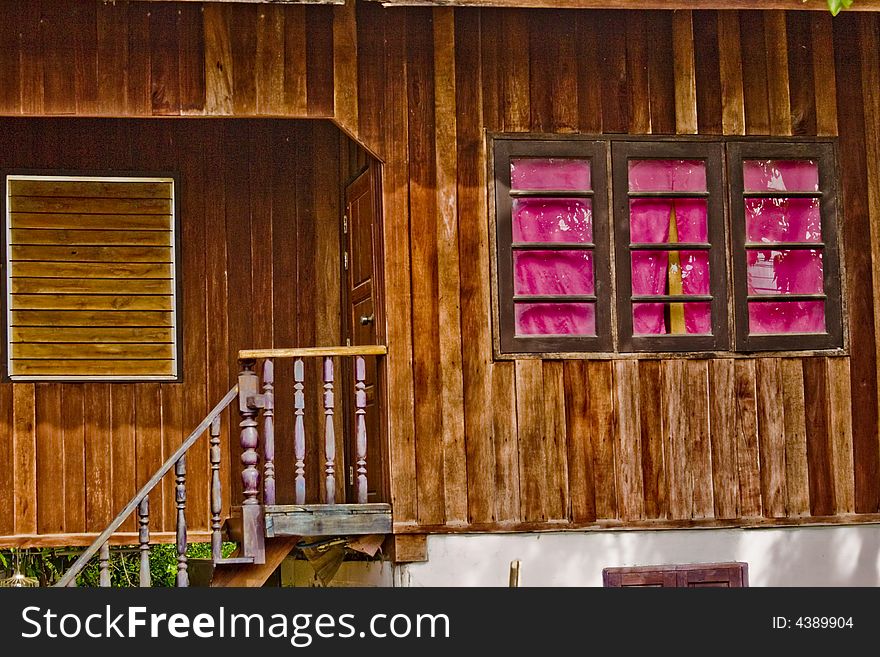 A wooden building with three pink windows