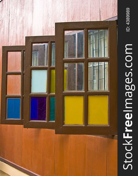 A wooden building with three colorful windows