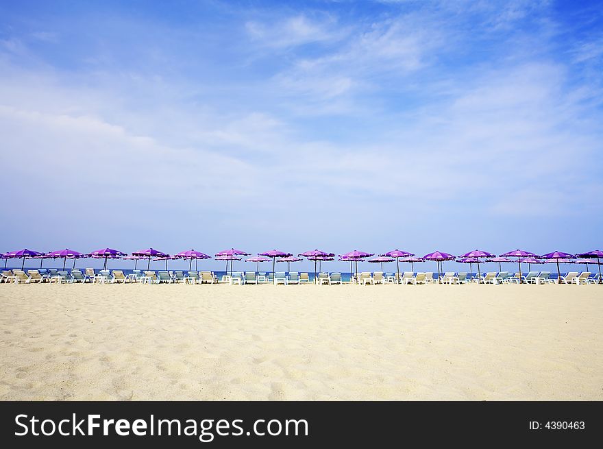 View of early morning summer beach with some chairs and umbrellas