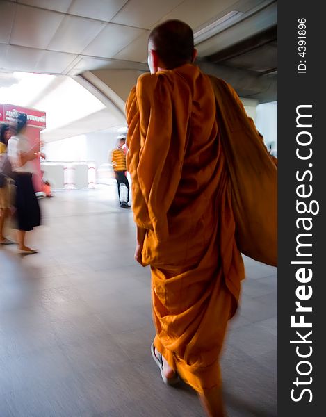 A monk with orange robes walking fast. A monk with orange robes walking fast