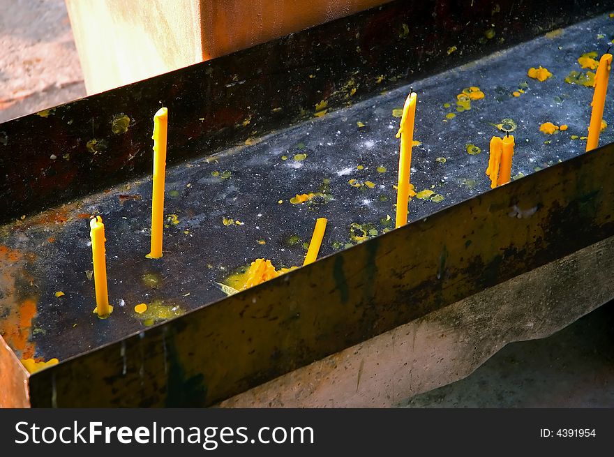 Yellow small candles that are being used at temple