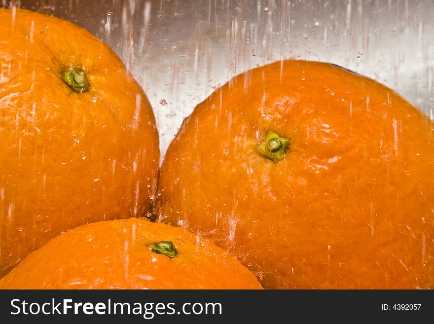 Lots of water drops falling on three oranges. Lots of water drops falling on three oranges