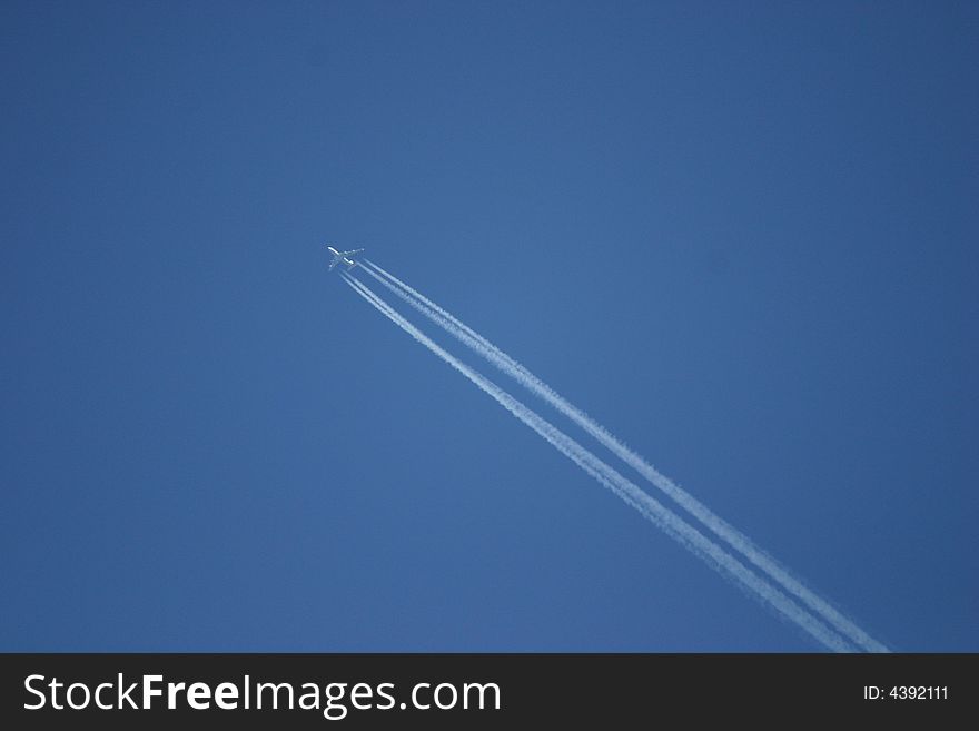 Airplane in the blue sky with condensation exhaust stripes