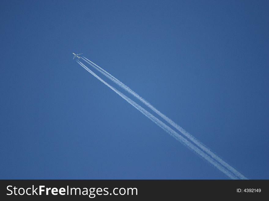 Airplane in the blue sky with condensated exhaust