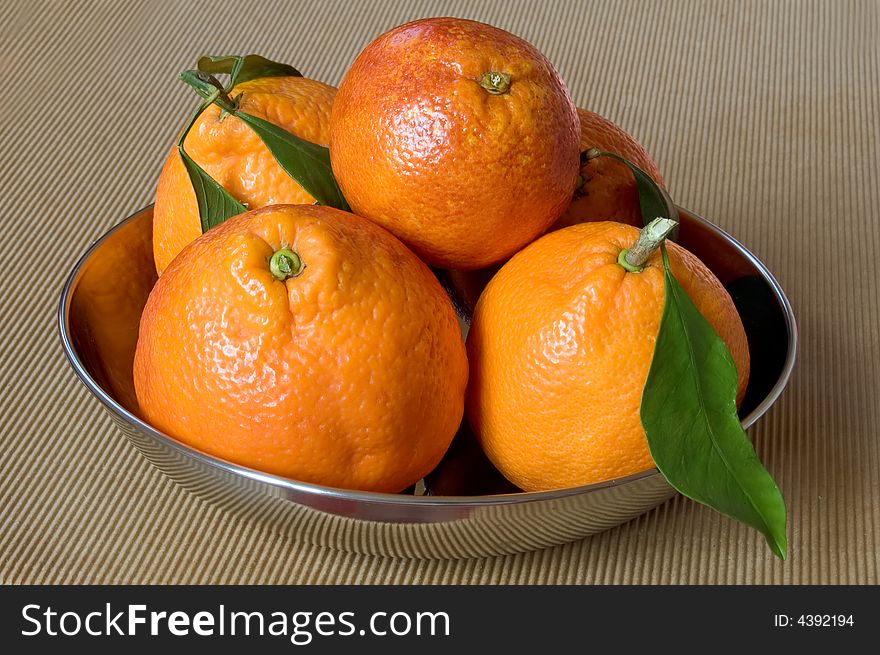 Five healthy oranges on a metallic plate