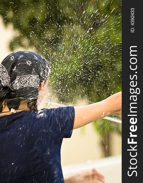 A girl gets sprayed in the face with water from a hose. A girl gets sprayed in the face with water from a hose