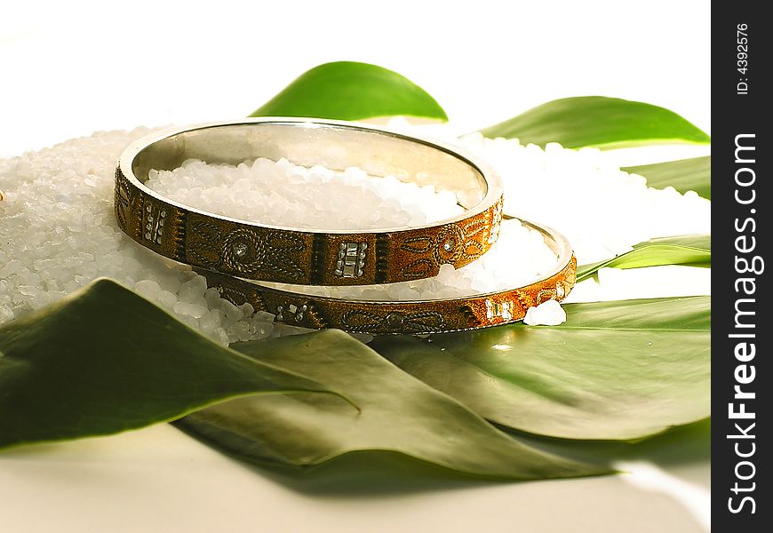 Two bracelets and bath salt on a green leaf