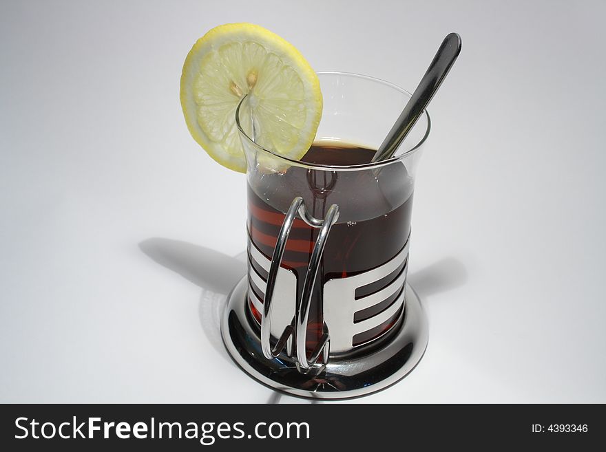 Modern glass of black tea with lemon and teaspoon. Modern glass of black tea with lemon and teaspoon