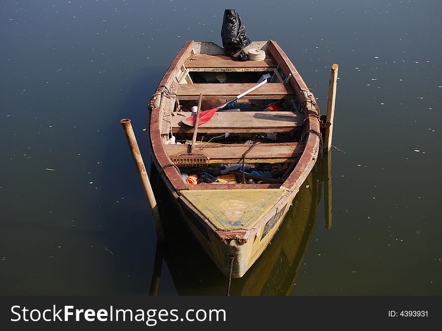 Old wooden boat beside pier with  oar