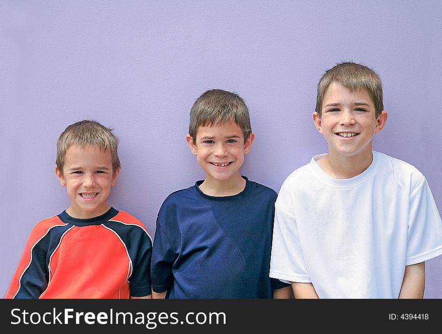 Three Brothers Posing Against a Purple Wall