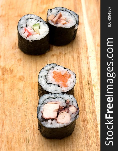 Four different sushi rolls on cutting board.