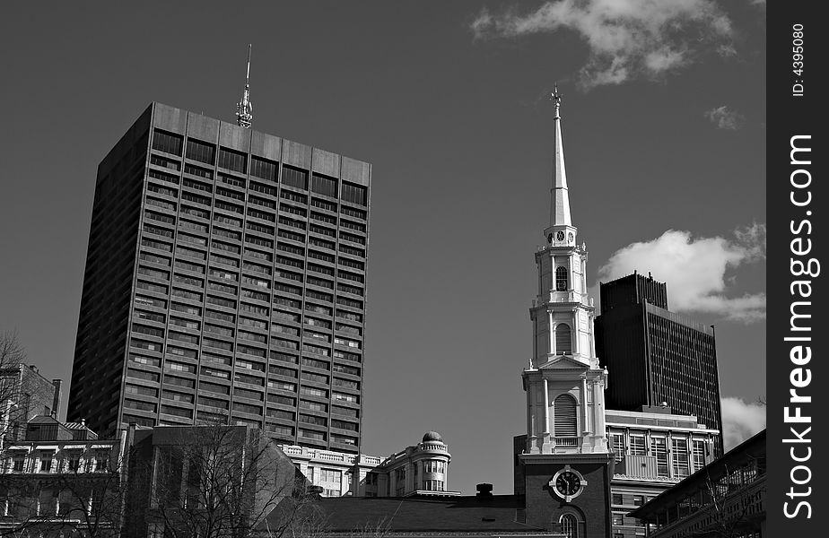 Downtown Boston showing the clock tower and steeple of Park Street Church surrounded by more modern buildings. Downtown Boston showing the clock tower and steeple of Park Street Church surrounded by more modern buildings