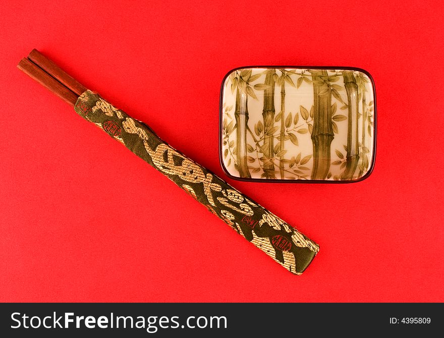 Bamboo design on a Japanese sushi bowl against red background with chopsticks. Bamboo design on a Japanese sushi bowl against red background with chopsticks