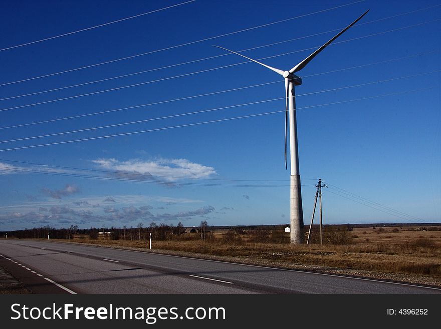 Windmill turbine behind electric lines generating power