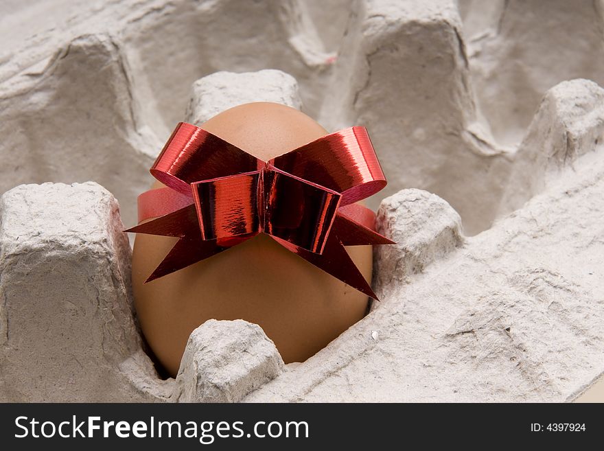 Brown egg  with red bow in a  carton box