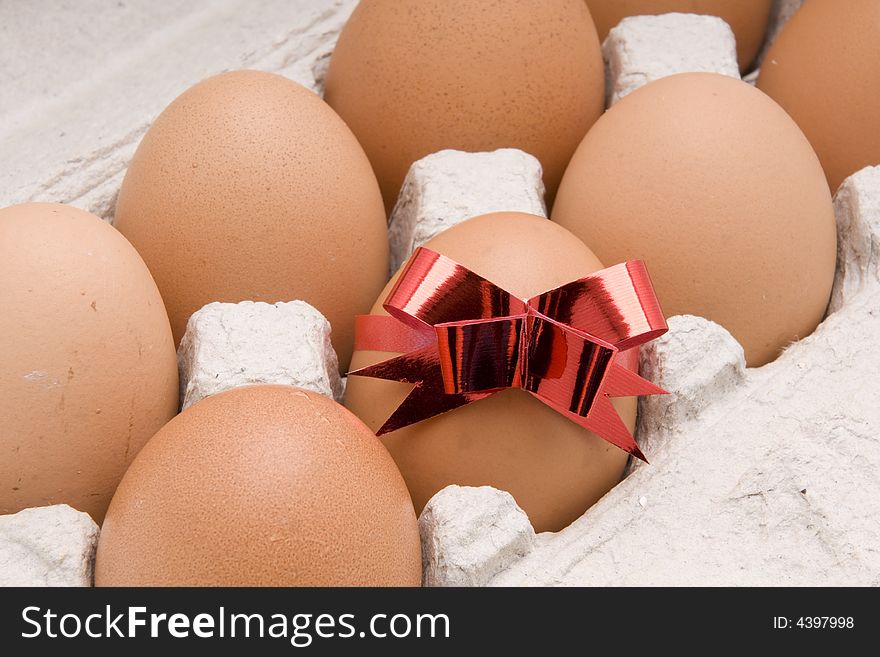 Brown egg  with red bow in a  carton box