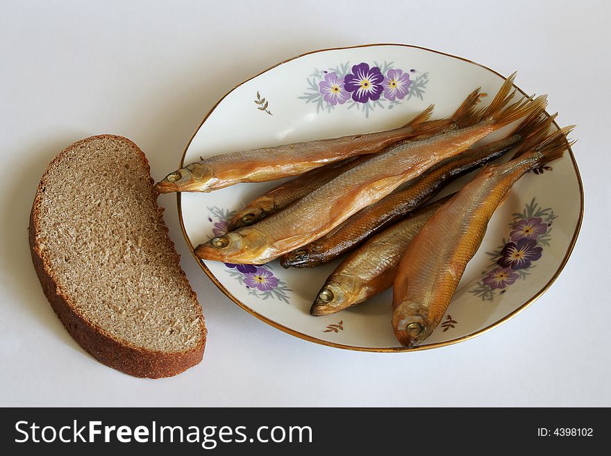 Smelt on a plate and a piece of rye bread. Smelt on a plate and a piece of rye bread
