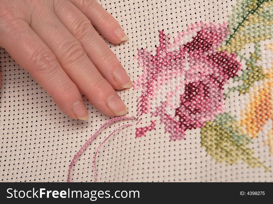 Woman embroidering a beautiful pink rose. Woman embroidering a beautiful pink rose