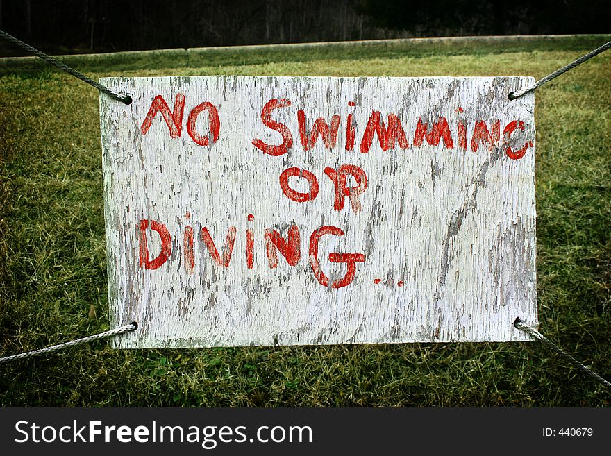 An old hand-painted sign hangs over green grass at a boat dock. An old hand-painted sign hangs over green grass at a boat dock.