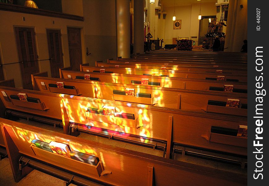 Stained glass light casts onto church pews. Stained glass light casts onto church pews.