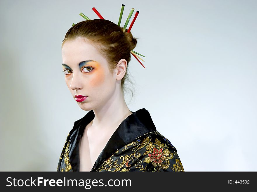 Attractive young woman wearing elaborate makeup with chopsticks in her hair bun. Attractive young woman wearing elaborate makeup with chopsticks in her hair bun