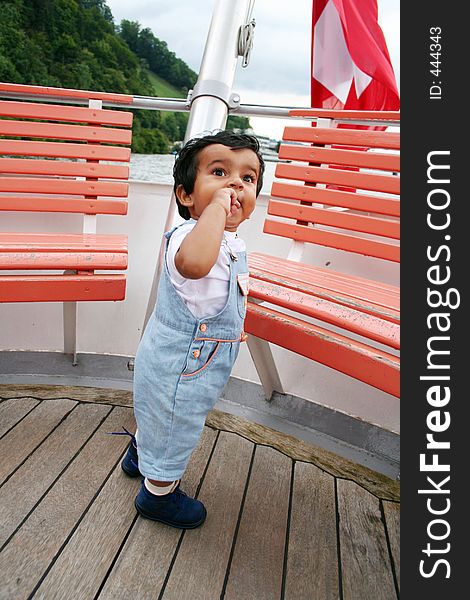 A kid in blue drees and blue shoes standing in a boat in switzerland. A kid in blue drees and blue shoes standing in a boat in switzerland.