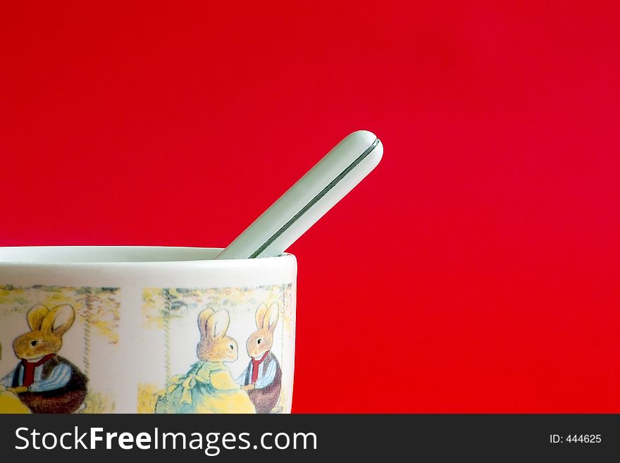 White milk cup with small spoon on a red background