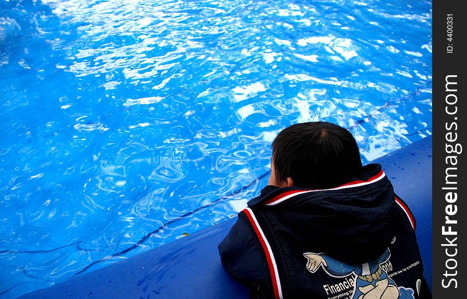 A Chinese kid stands looking into the blue clear glittering cleanpeaceful ,glittering water,.The water facea is the reflection of the blue,azure sky . A Chinese kid stands looking into the blue clear glittering cleanpeaceful ,glittering water,.The water facea is the reflection of the blue,azure sky .