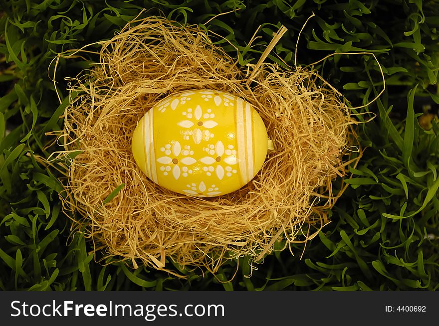 Easter egg in nest on green grass.