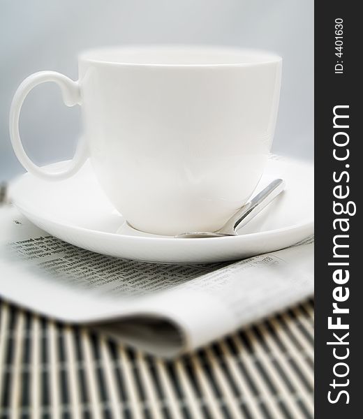 Coffee cup and newspaper on a table. Coffee cup and newspaper on a table