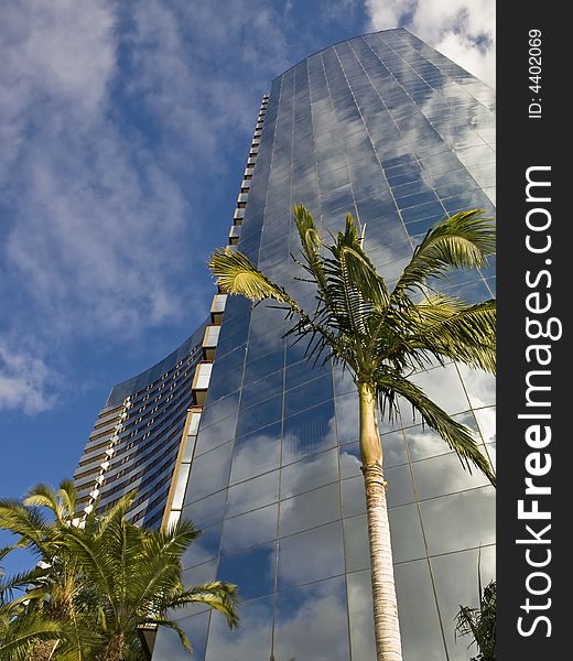 Glass skyscraper reflects sky with clouds in tropics. Glass skyscraper reflects sky with clouds in tropics
