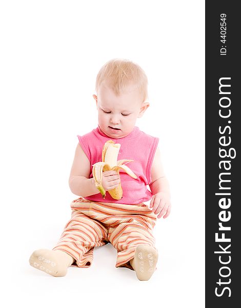 A small girl sitting on the floor and eating a banana. A small girl sitting on the floor and eating a banana