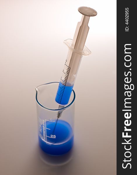 Syringe and measuring glass with blue liquid. Syringe and measuring glass with blue liquid