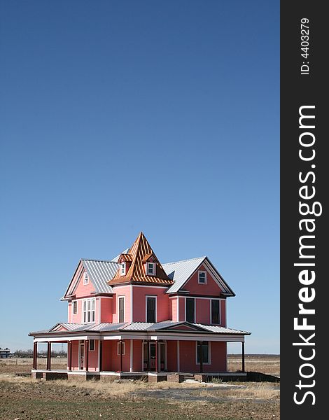 A pink Victorian style 19th century house with a clear blue sky. A pink Victorian style 19th century house with a clear blue sky.