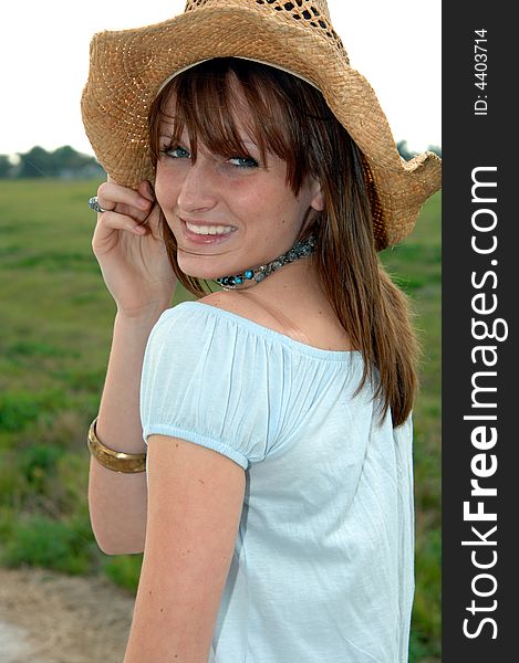 A smiling young women wearing a cowboy hat outdoors. A smiling young women wearing a cowboy hat outdoors