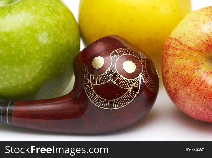 Close-up of long ornamented north-caucasian pipe with multicolored apples at white background. Close-up of long ornamented north-caucasian pipe with multicolored apples at white background