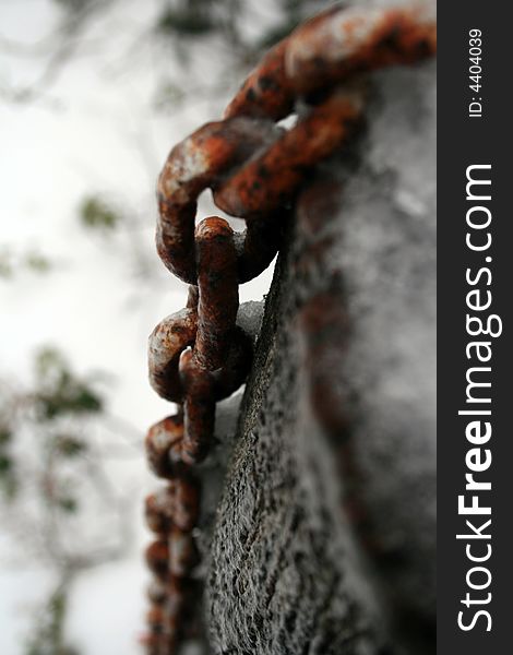 Old Orange rusted chain frozen to wooden post. Old Orange rusted chain frozen to wooden post