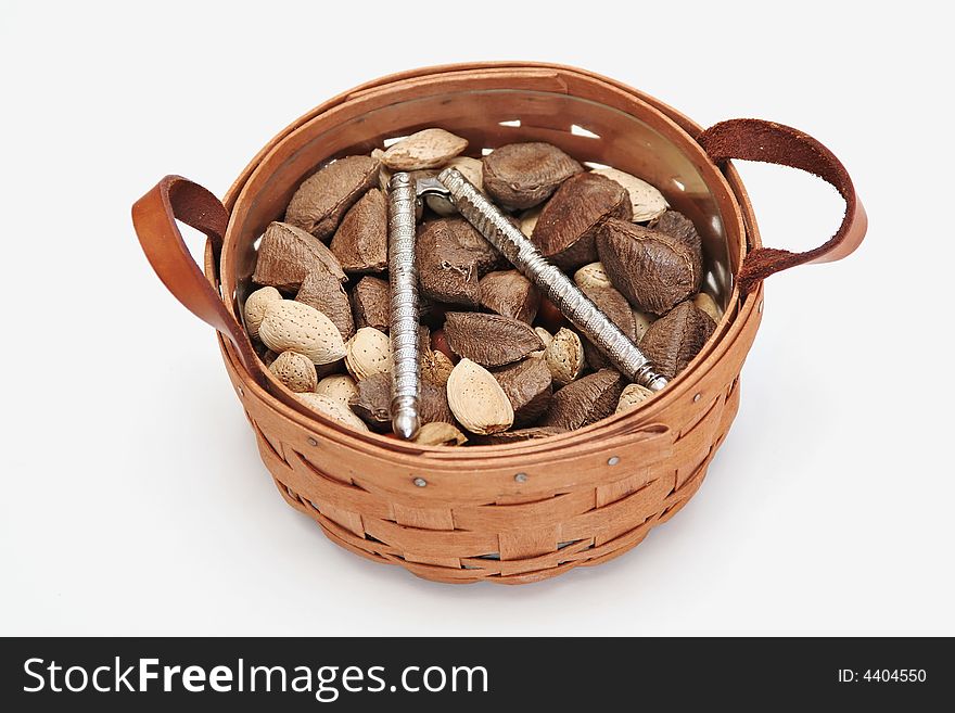 A woven wood basket filled with almonds, brazil nuts and nut cracker on white background. A woven wood basket filled with almonds, brazil nuts and nut cracker on white background