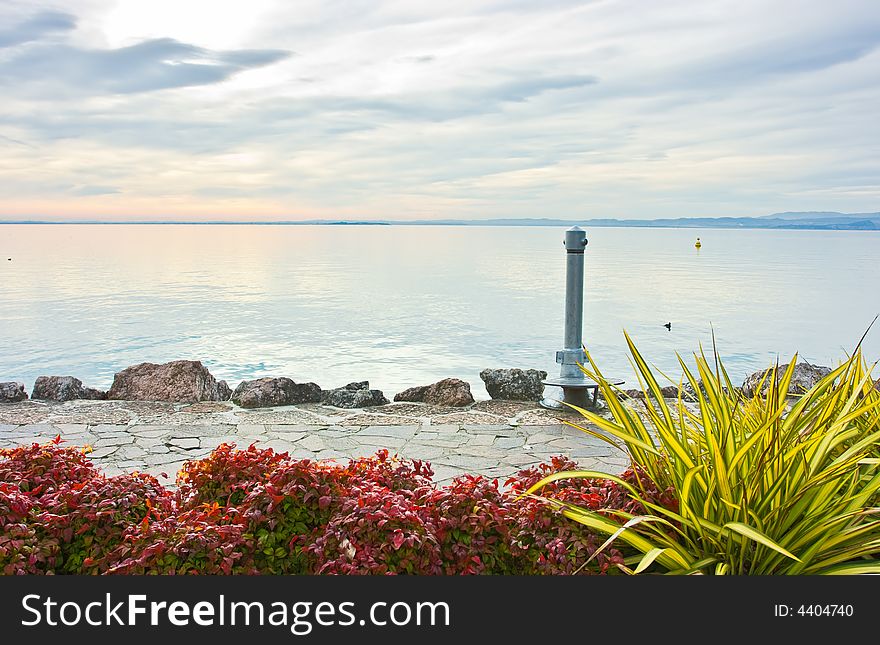 Cloudy drammatic sunset over lake Garda renders colors pastel and scenery serene