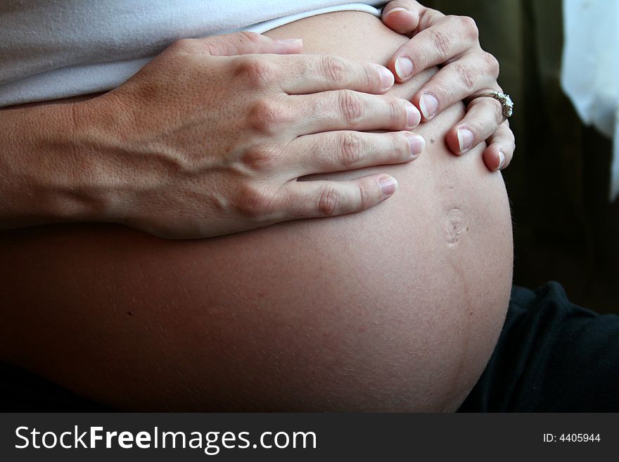 An expecting mother holds her stomach lovingly. An expecting mother holds her stomach lovingly.