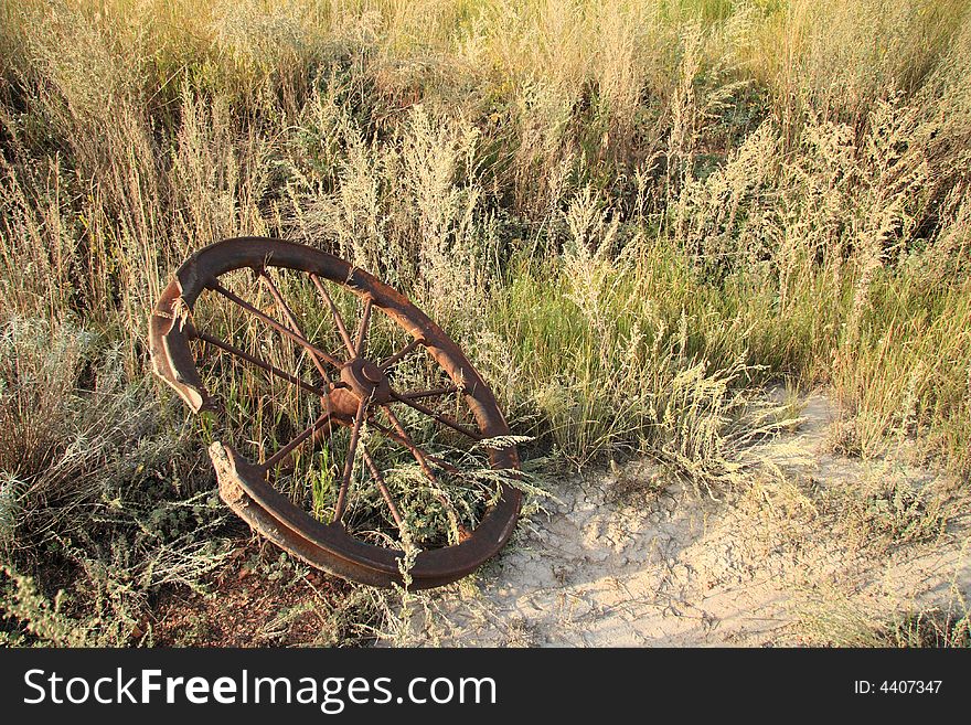 A rusty old steel pulley laying in the arid bush. A rusty old steel pulley laying in the arid bush