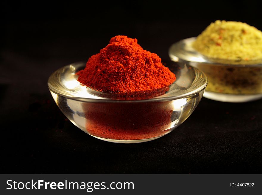 Red paprika in a glass bowl with mixed herbs on the background. Red paprika in a glass bowl with mixed herbs on the background