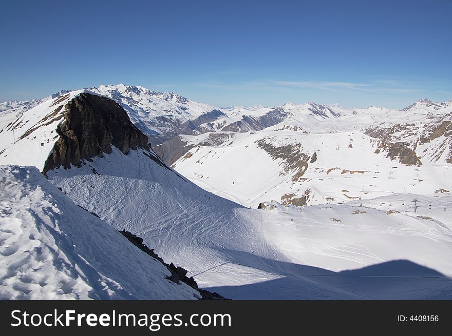 A panoramic view on Alps snow winter mountains chain under blue sky. A panoramic view on Alps snow winter mountains chain under blue sky.