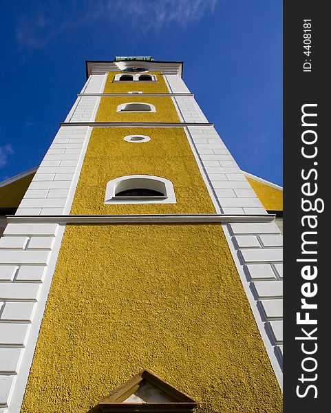 Yellow and white bell tower against deep blue sky. Yellow and white bell tower against deep blue sky