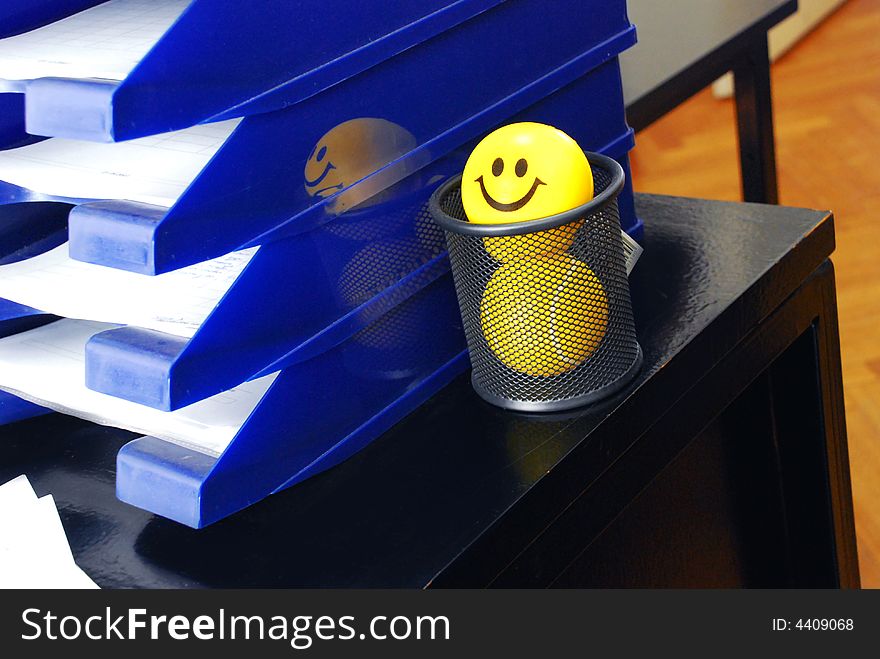 Yellow smiley ball in pen box of office desk