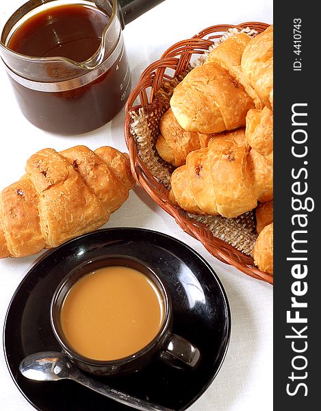 Cup of coffee with fresh croissants close-up view