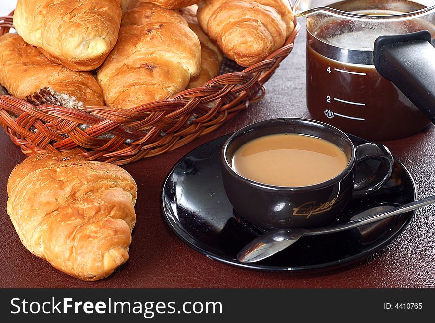 Cup of coffee with fresh croissants close-up view