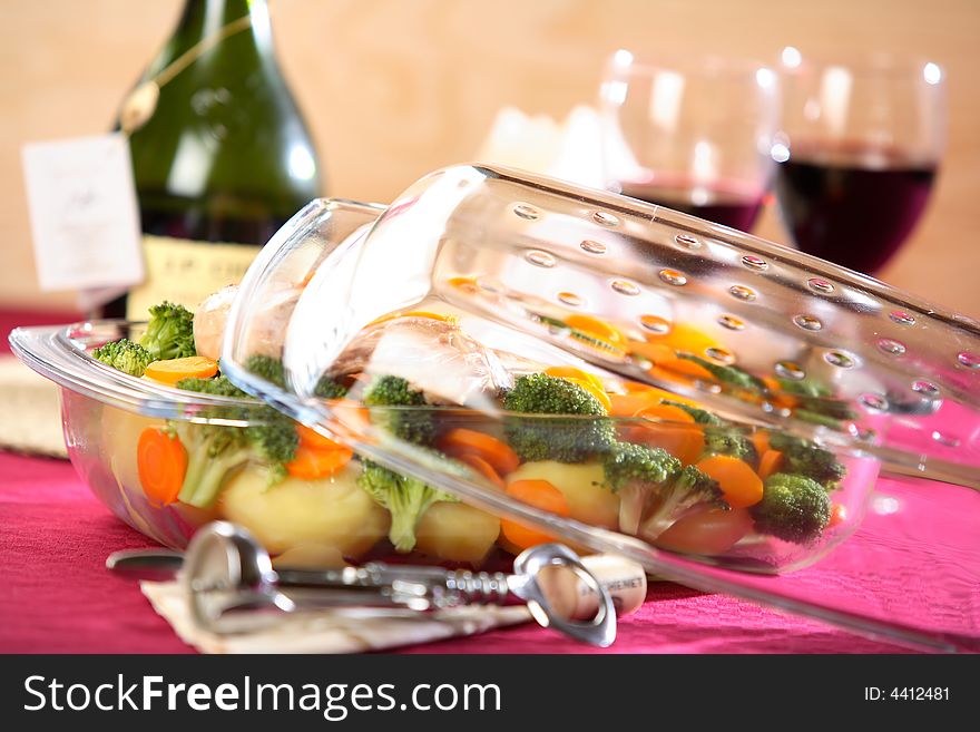 Boiled vegetables in oven-proof dish and bootle of wine