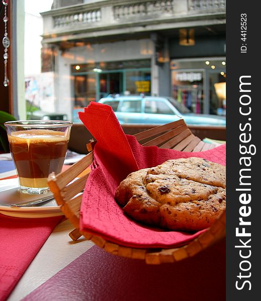 Coffee with chocolate biscuits, window fund in town with a blue car and old architecture