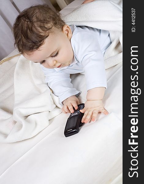 The little boy of 7 months plays with a cellular telephone.